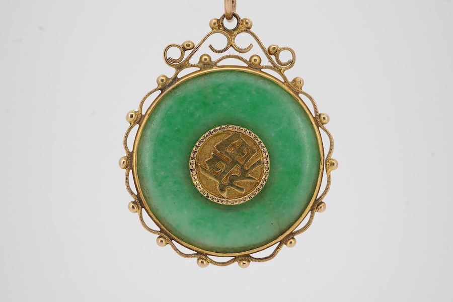 A Chinese yellow metal mounted carved jade 'Shou Fu' pendant, 36mm, on a gilt metal chain. Condition - fair to good